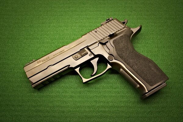 Pistolet Model SIG Sauer P226. Nowoczesna broń. Pistolet na zielonym tle