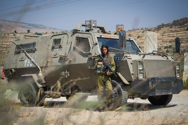 A girl on the background of armored vehicles