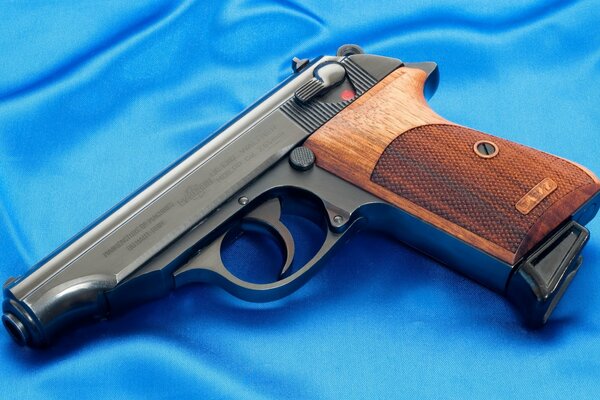 Pistolet samopowtarzalny Model Walther PP leżący na niebieskiej tkaninie
