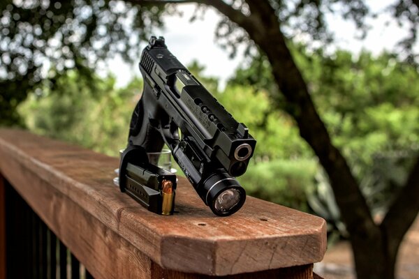 Pistolet avec lampe de poche sur balustrade en bois