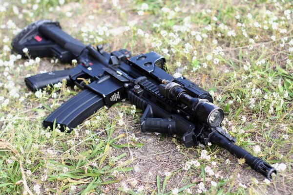 HK416 submachine gun lying on the grass. German automatic from the company Heckler & Koch. The machine is black