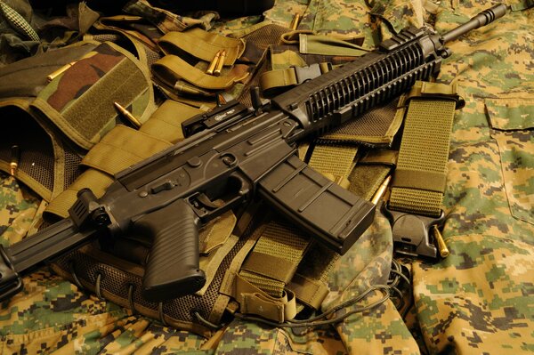 An assault rifle is lying on a military uniform