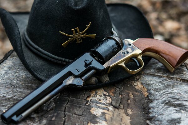 A black hat and a revolver are lying on the bark of a tree