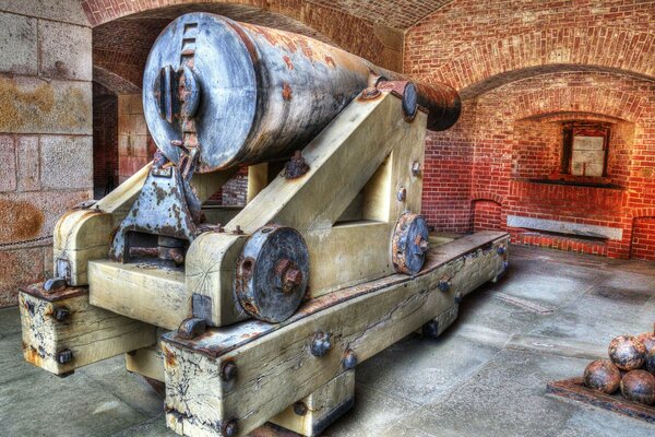 An old wooden cannon is aimed at a brick wall