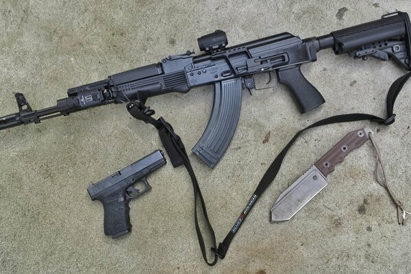 Knife, pistol and carbine on a gray background