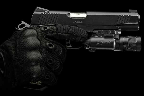 Una mano en un guante de seguridad negro sostiene una pistola