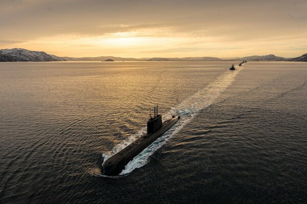 Los submarinos navegan por el mar en medio de la puesta de sol