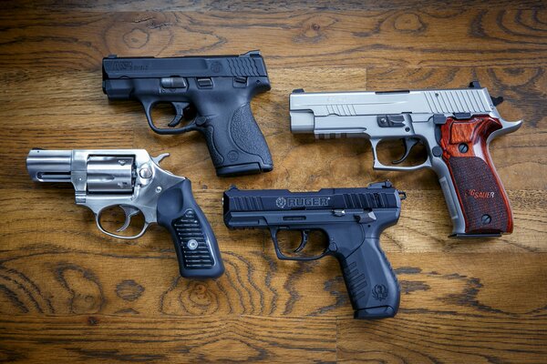 Vier Pistolen verschiedener Marken auf einer Holzoberfläche