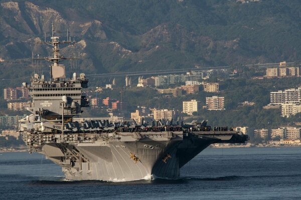 An aircraft carrier with a nuclear power plant in the sea against the background of the city