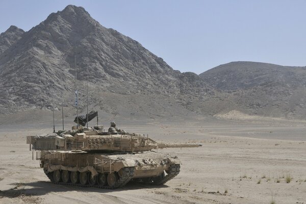 Battle tank in the desert on the background of a mountain