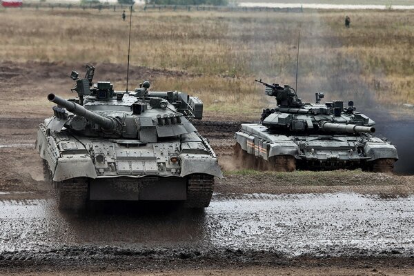 Tanques T-80 y T-90 en un campo de entrenamiento militar sucio