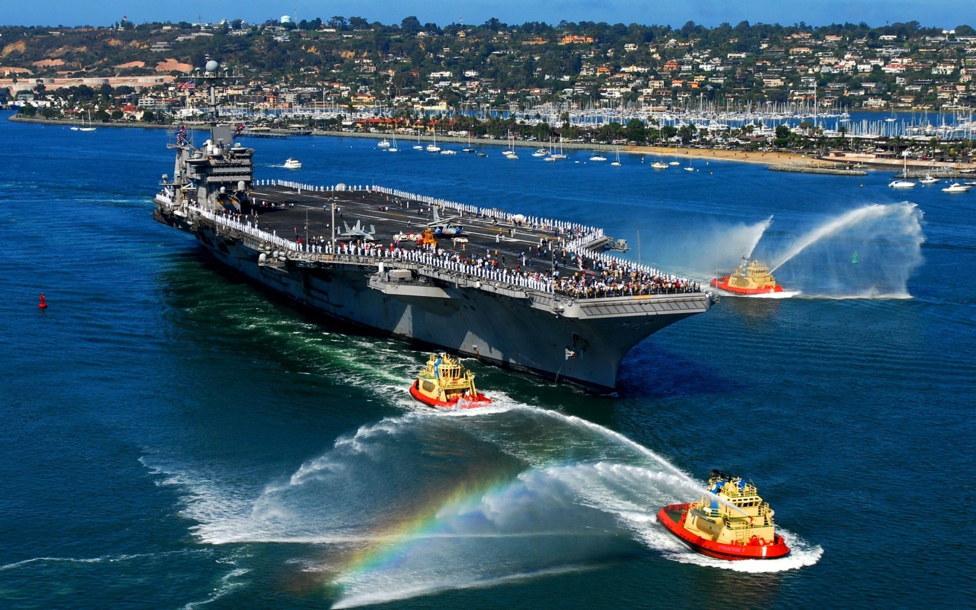 puerto portaaviones barcos pequeños saludo chorros de agua arco iris