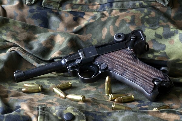 A pistol with scattered cartridges on a camouflage uniform