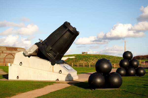 Cannon and cannonballs on the grass by the path