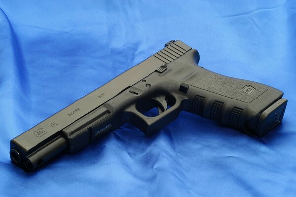 Czarny pistolet Glock 17L na niebieskim tle