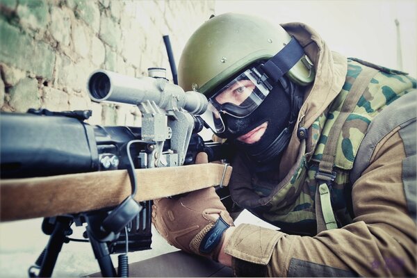 Sniper in helmet and camouflage of the Ministry of Internal Affairs takes aim