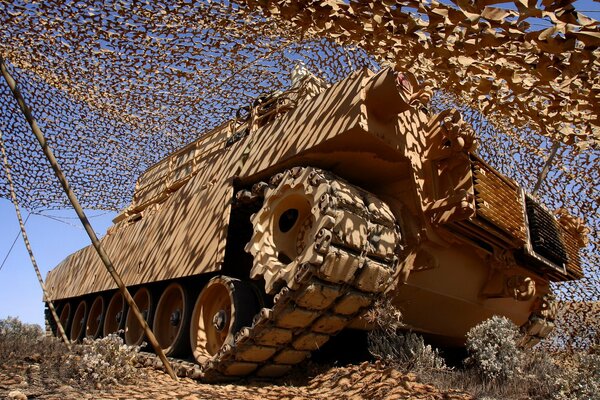 A brown tank under a camouflage net