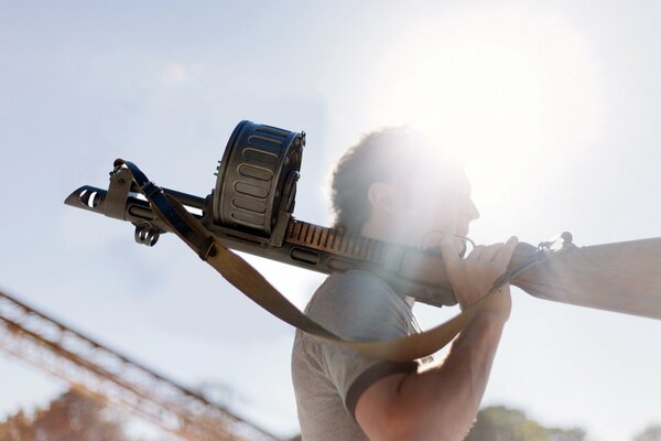 A guy with a machine gun on his shoulder under the sun