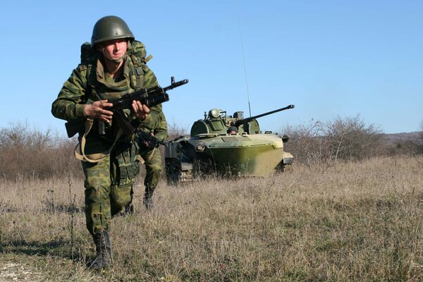 A soldier with a machine gun runs across the field