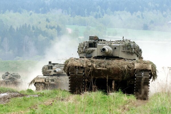 Several tanks are driving across the field