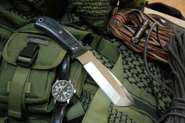 Background with a knife and a watch on a green bag