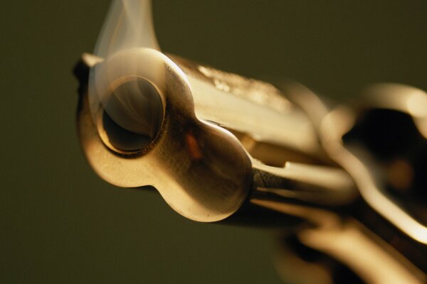 Macro pistols with a muzzle in the foreground and smoke coming out of it