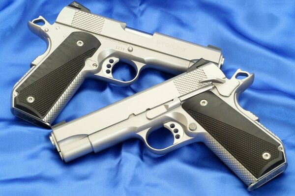 Два пистолета серебряного цвета на синем шелке