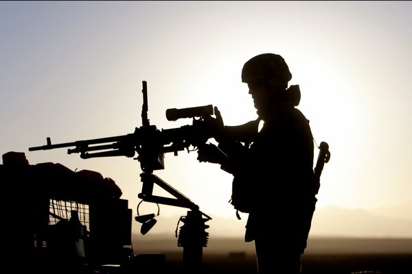 Silueta de un soldado con una ametralladora al atardecer