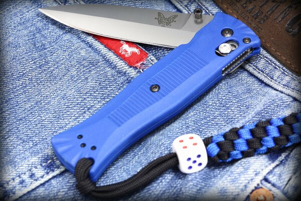 A folding blue knife is lying on the jeans