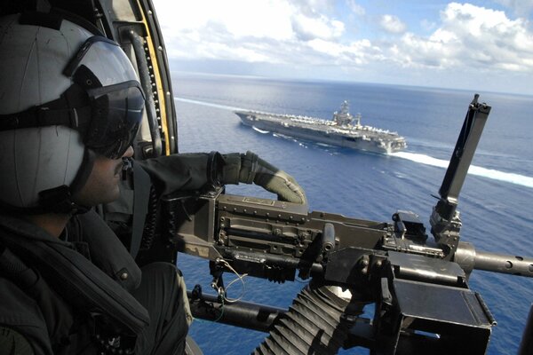 Ein militärisches Maschinengewehr mit einem Hubschrauber begleitet das Schiff