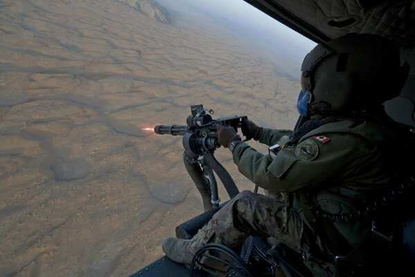 Un soldat en hélicoptère tire une mitrailleuse