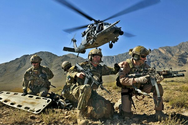 Soldados con camillas y armas bajo un helicóptero