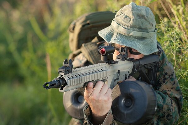 Dans les buissons verts assis un homme avec des armes