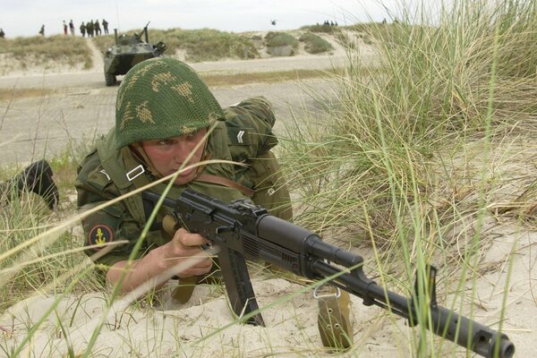 Sur le terrain dans les buissons est un homme avec des armes