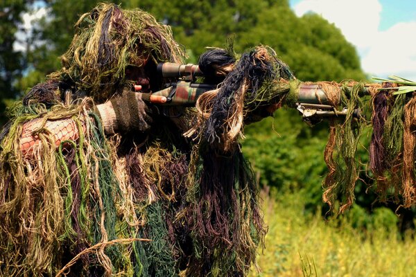 Scharfschütze in Gras-Tarnung mit Maschinengewehr