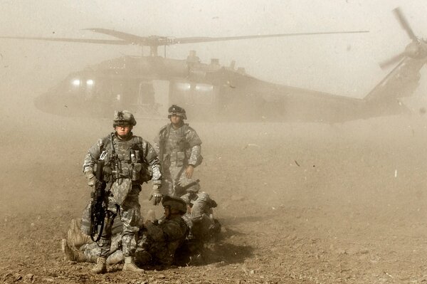 Soldats devant l hélicoptère dans la poussière