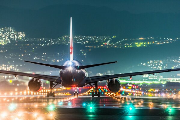 Avión de pasajeros en las luces de la ciudad nocturna