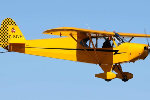 Pilote dans le ciel clair sur un avion rétro jaune