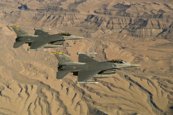 Two f-16 Fighting falcons fly against the background of the desert