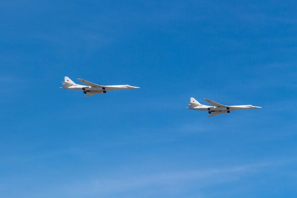 Two fighter planes are flying across the blue sky