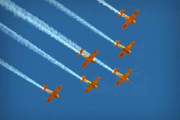 A squadron of yellow planes is flying in the blue sky