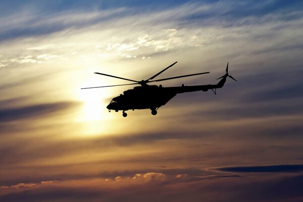 Elicottero che vola sullo sfondo del sole al tramonto