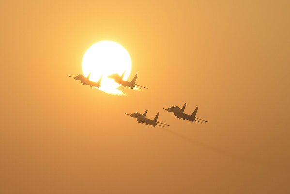 Les chasseurs su-27 volent sur fond de soleil