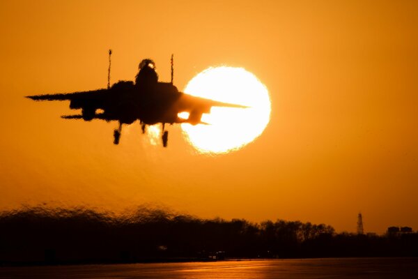 Un avión vuela en el fondo de una hermosa puesta de sol