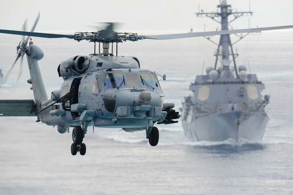 The ship s multi - purpose helicopter SH - 60f flies against the background of a warship