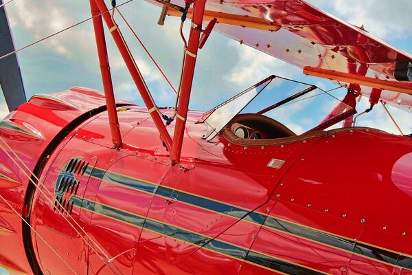 The cabin of a red biplane and clouds