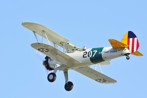 El biplano US Coast Guard vuela en el cielo azul