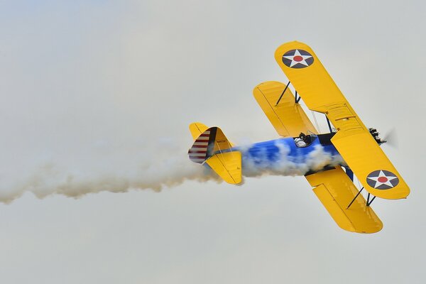 A biplane plane with smoke flies on parade