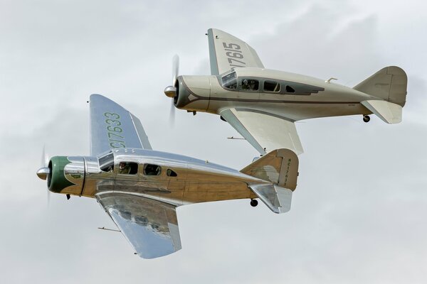 Deux avions légers en vol sur fond de nuages épais blancs