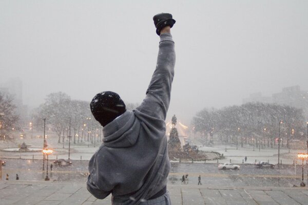 Guy debout dos levé la main vers le haut, il neige, la place Pouchkine